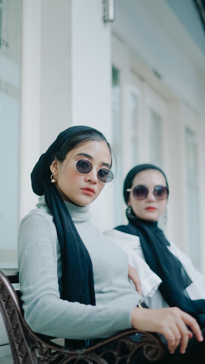 Two fashionable women with sunglasses and elegant attire in an outdoor setting in Indonesia.